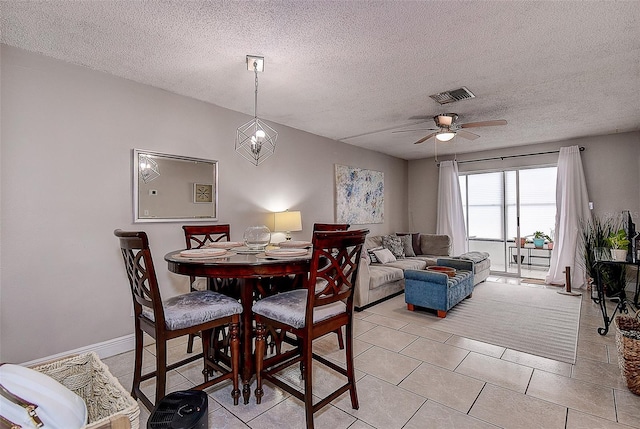 dining space featuring light tile patterned floors, a textured ceiling, and ceiling fan