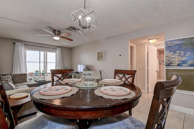 dining room with a textured ceiling, ceiling fan with notable chandelier, and light tile patterned floors