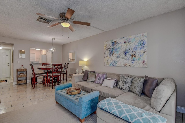 living room featuring ceiling fan, a textured ceiling, and light tile patterned floors