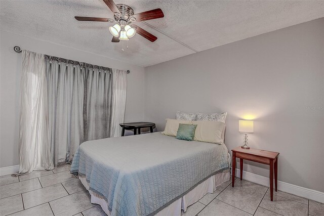 tiled bedroom with ceiling fan and a textured ceiling