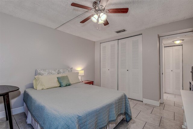 tiled bedroom with a textured ceiling and ceiling fan