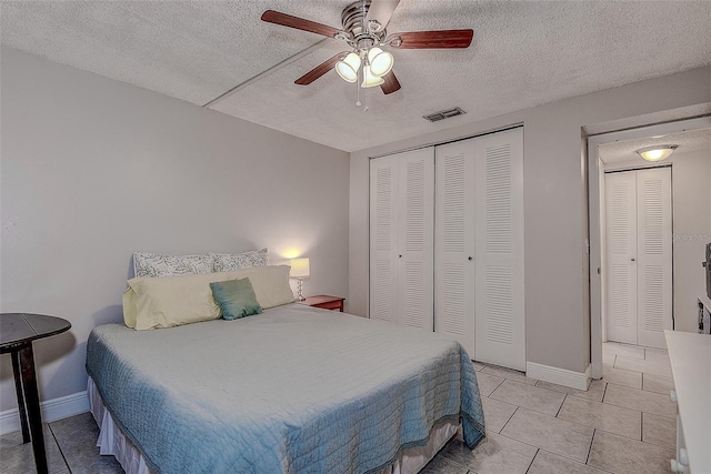 bedroom with ceiling fan, light tile patterned floors, a textured ceiling, and a closet