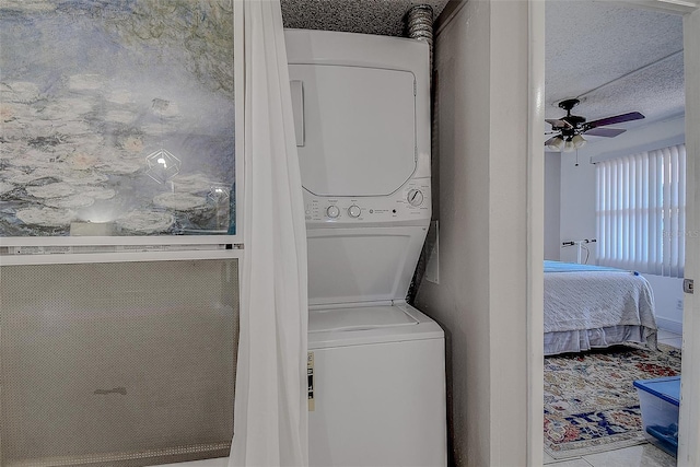 laundry area featuring stacked washer and dryer, a textured ceiling, and ceiling fan