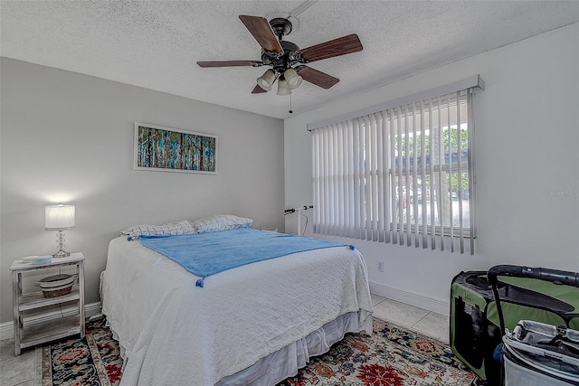 bedroom featuring ceiling fan, a textured ceiling, and light tile patterned floors