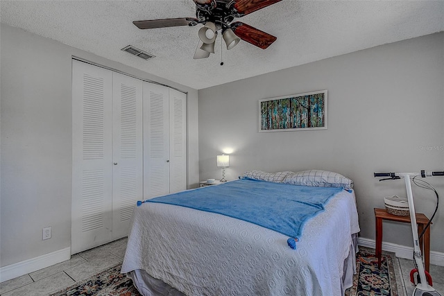 bedroom featuring a textured ceiling, a closet, ceiling fan, and light tile patterned floors