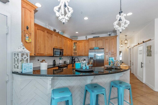 kitchen with stainless steel appliances, decorative backsplash, a kitchen breakfast bar, pendant lighting, and kitchen peninsula