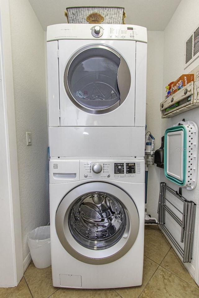 laundry area featuring light tile patterned floors and stacked washer and dryer