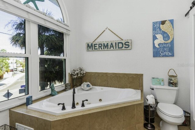 bathroom featuring toilet and tiled tub