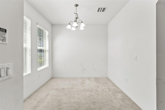 carpeted spare room with an inviting chandelier