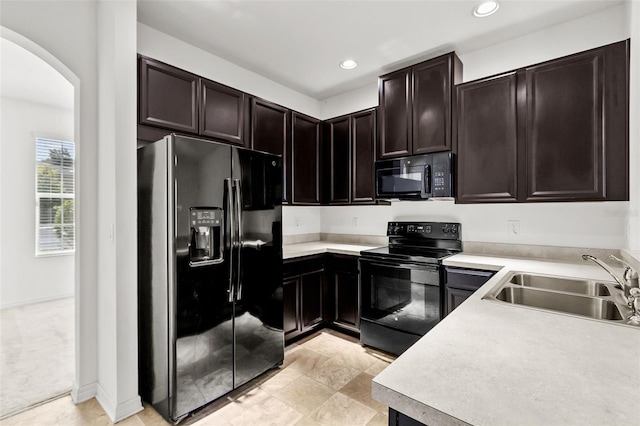 kitchen featuring black appliances, sink, dark brown cabinetry, and light colored carpet