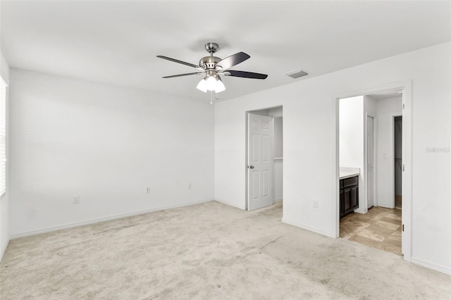 unfurnished bedroom with ensuite bathroom, ceiling fan, and light colored carpet