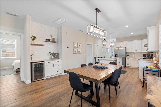 dining room featuring light hardwood / wood-style flooring, wine cooler, and sink