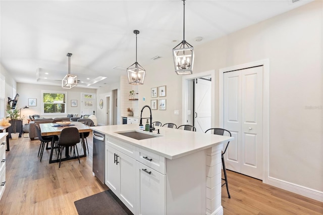 kitchen featuring a kitchen island with sink, sink, pendant lighting, light hardwood / wood-style floors, and a breakfast bar area