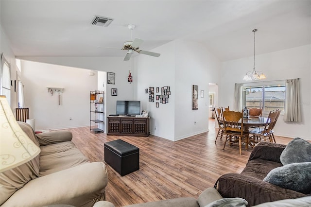 living room featuring light hardwood / wood-style floors, ceiling fan with notable chandelier, and high vaulted ceiling