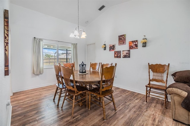 dining area featuring high vaulted ceiling, an inviting chandelier, and hardwood / wood-style flooring