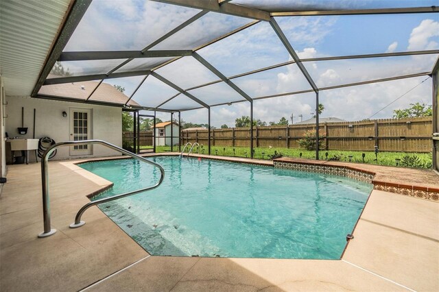 view of pool with a patio, glass enclosure, and a shed