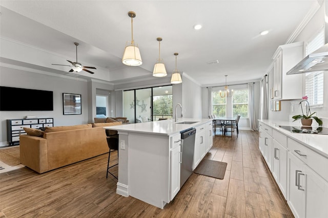 kitchen with stainless steel dishwasher, white cabinets, an island with sink, and ornamental molding