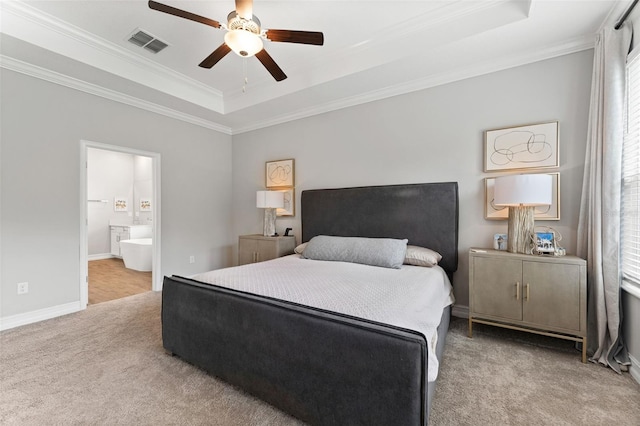 bedroom with carpet floors, ensuite bath, ornamental molding, a tray ceiling, and ceiling fan