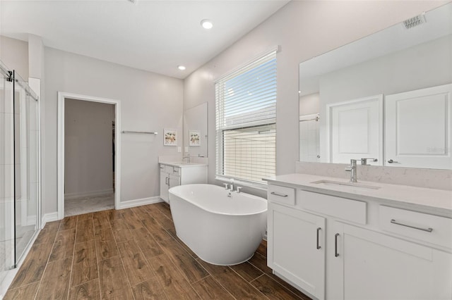 bathroom featuring wood-type flooring, dual bowl vanity, and plus walk in shower