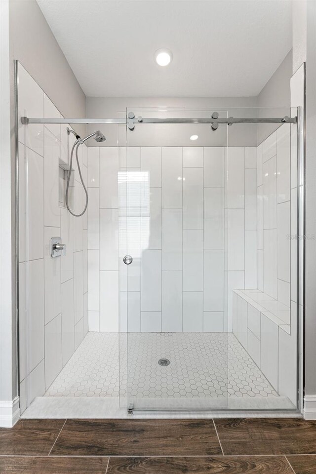 bathroom with hardwood / wood-style floors and a shower with shower door