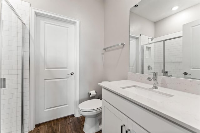 bathroom with hardwood / wood-style flooring, vanity, toilet, and a shower with shower door