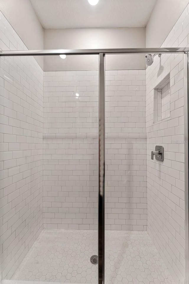 bathroom with a textured ceiling and a shower with shower door