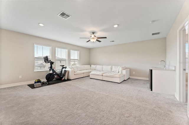 living room featuring ceiling fan, sink, and light carpet