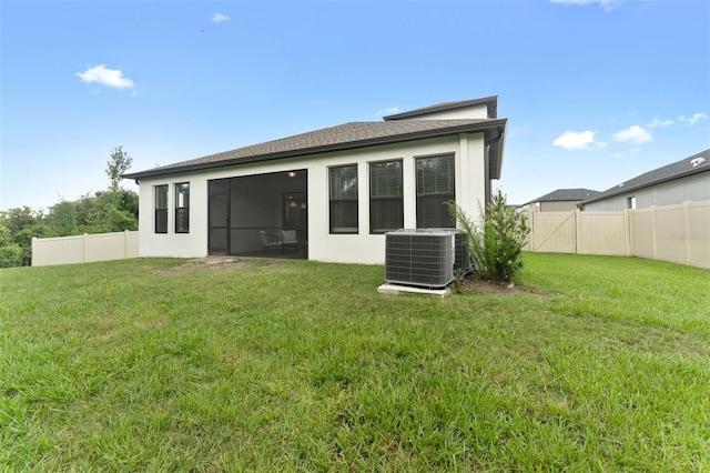 rear view of house with central AC, a yard, and a sunroom