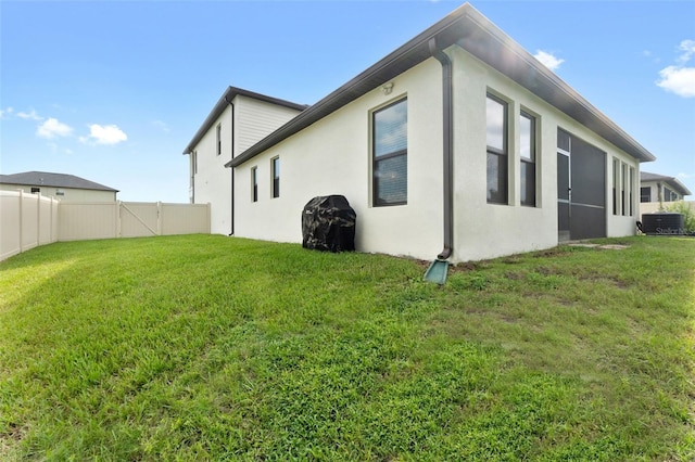 view of side of property with a yard and central AC