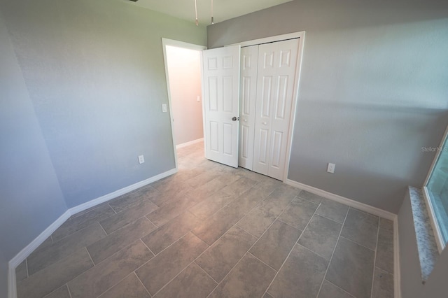 unfurnished bedroom with a closet and baseboards