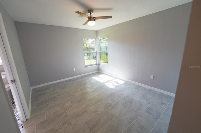 spare room with ceiling fan and baseboards