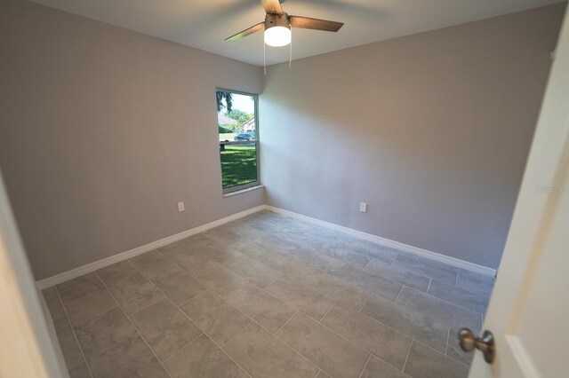 empty room with a ceiling fan and baseboards