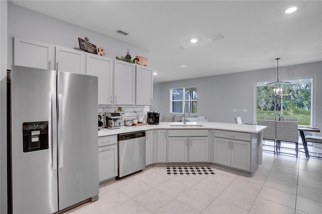 kitchen featuring sink, stainless steel appliances, kitchen peninsula, and decorative light fixtures