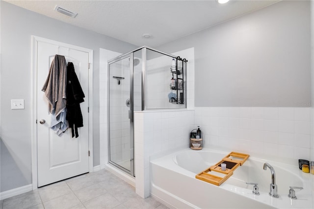 bathroom with a textured ceiling, plus walk in shower, and tile patterned floors