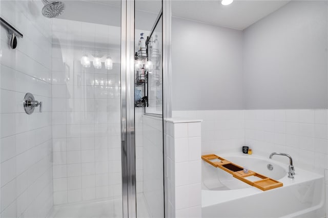 bathroom featuring tile walls and separate shower and tub