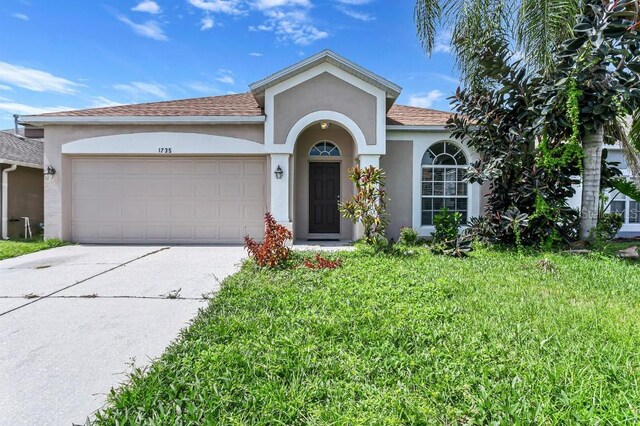 single story home with a garage and a front lawn