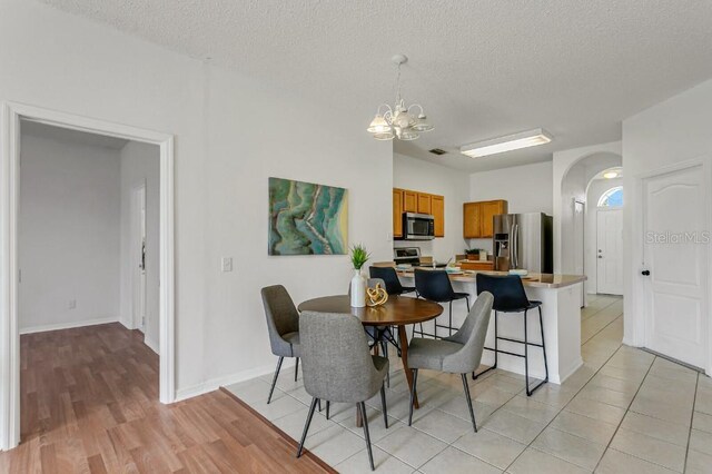 dining room featuring light hardwood / wood-style floors, a textured ceiling, and a notable chandelier