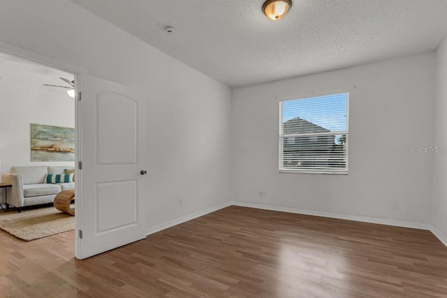 empty room with hardwood / wood-style flooring, ceiling fan, and a textured ceiling