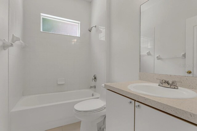 full bathroom featuring tile patterned flooring, vanity, toilet, and tiled shower / bath combo