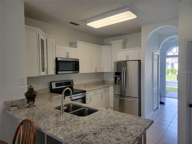 kitchen featuring sink, a textured ceiling, white cabinetry, kitchen peninsula, and stainless steel appliances