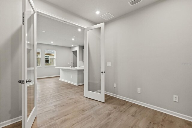 interior space with light hardwood / wood-style flooring, sink, and french doors