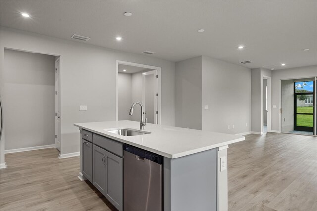 kitchen with light wood-type flooring, dishwasher, an island with sink, sink, and gray cabinetry