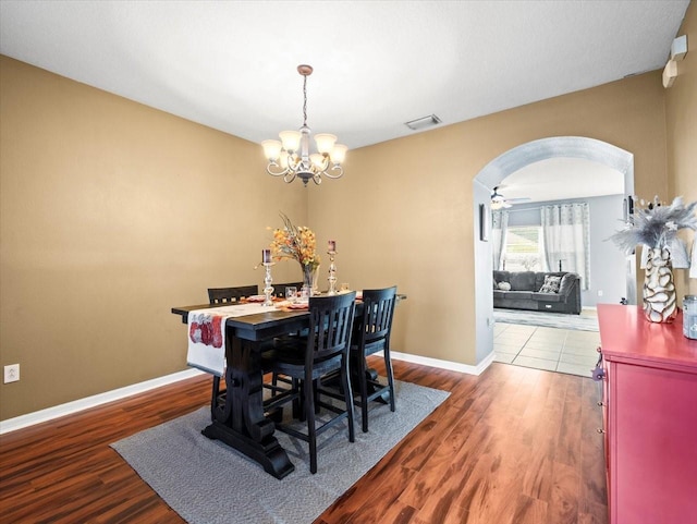 dining area with ceiling fan with notable chandelier and wood-type flooring