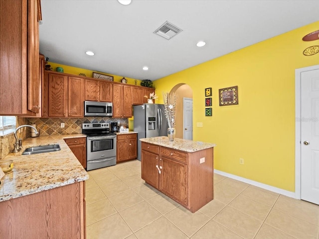 kitchen with backsplash, light tile patterned floors, sink, a center island, and stainless steel appliances