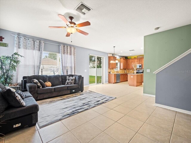 living room with ceiling fan with notable chandelier and light tile patterned flooring