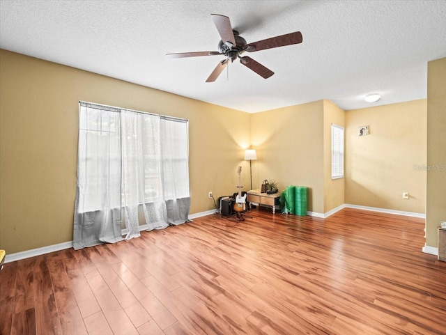 sitting room with ceiling fan, a textured ceiling, and wood-type flooring