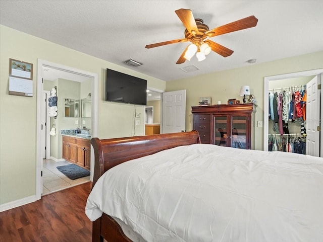 bedroom featuring a walk in closet, ensuite bath, a closet, ceiling fan, and light tile patterned floors