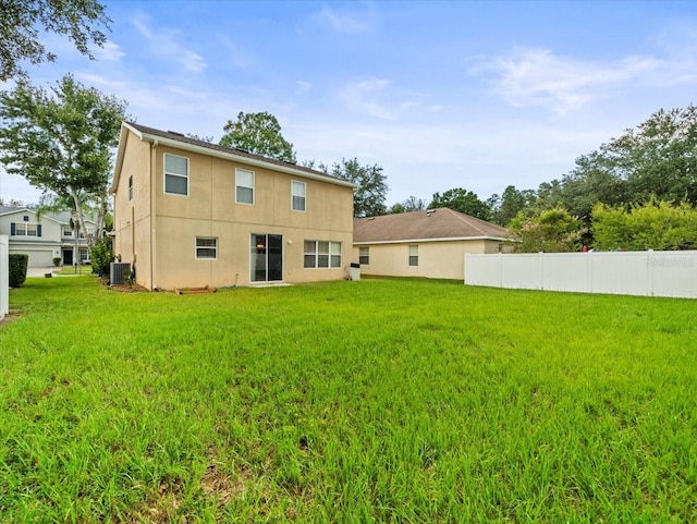 rear view of property featuring cooling unit and a yard