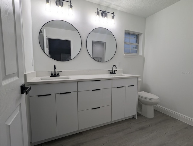 bathroom with vanity, toilet, hardwood / wood-style floors, and a textured ceiling