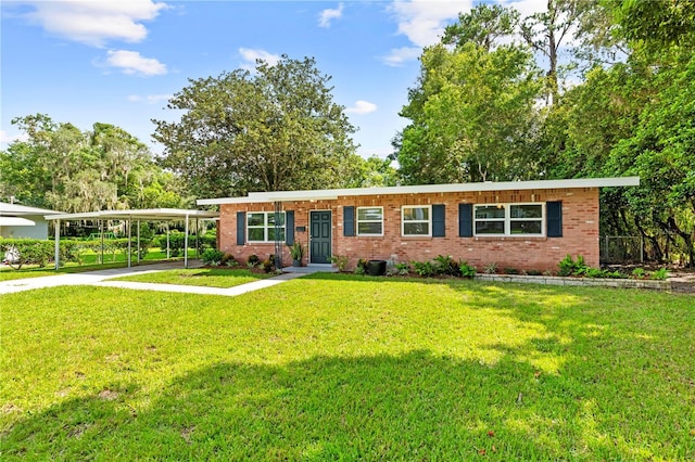 single story home with a detached carport, concrete driveway, a front lawn, and brick siding